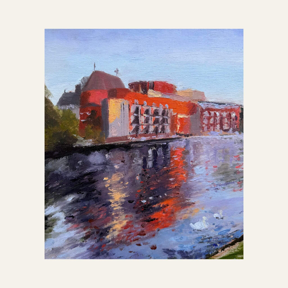 Close-up of the Royal Shakespeare Theatre in warm autumn colours, with red, orange and blue reflections on the River Avon.