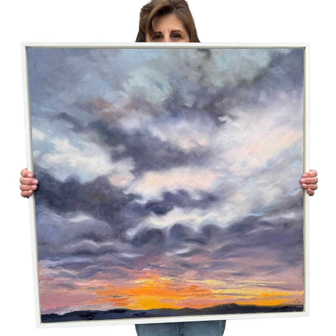 Close-up of framed oil painting depicting a dramatic early morning sunrise, set in a clean white wooden frame