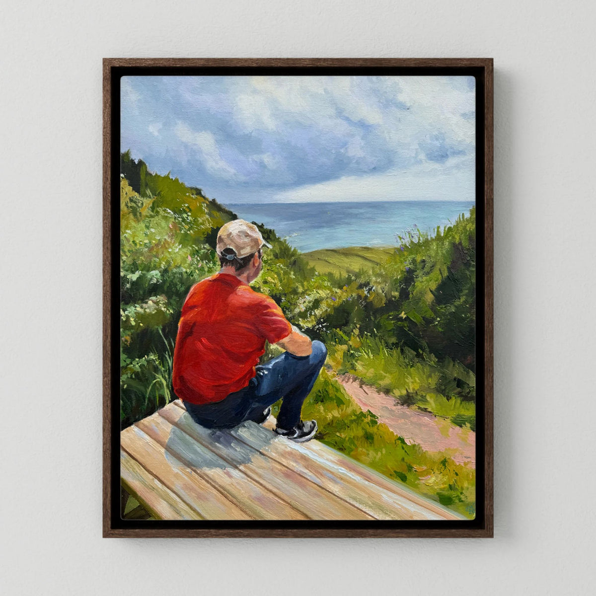 Just taking it in canvas print in a dark oak frame, depicting a seated person looking across green countryside beneath a cloud-filled sky.
