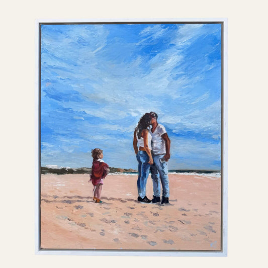 Mama by Lorraine Field, a framed oil painting of a couple embracing on a sandy beach with a young child nearby beneath a blue sky.