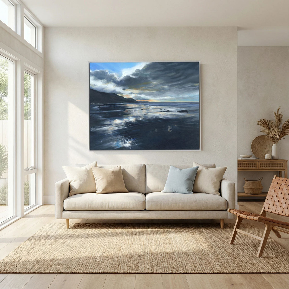 Stormy Seas canvas print displayed above a cream sofa in a bright living room, with blue-grey waves and storm clouds.