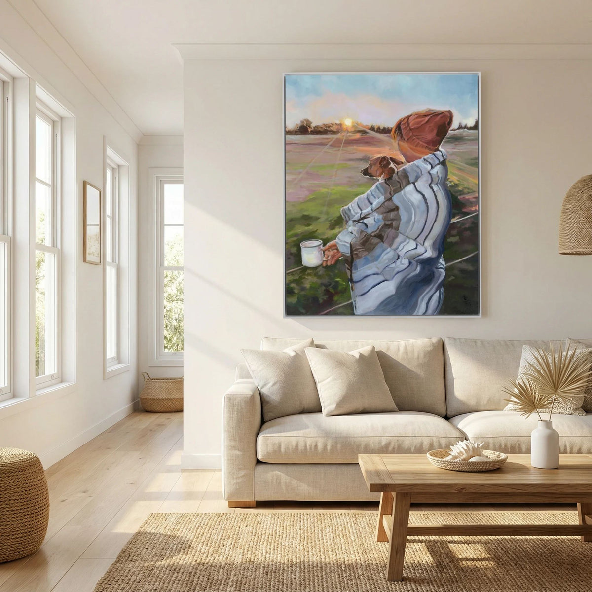 Sunrise With the Pup canvas print by Lorraine Field above a cream sofa, showing a person in a rust-coloured hat holding a small dog at sunrise.