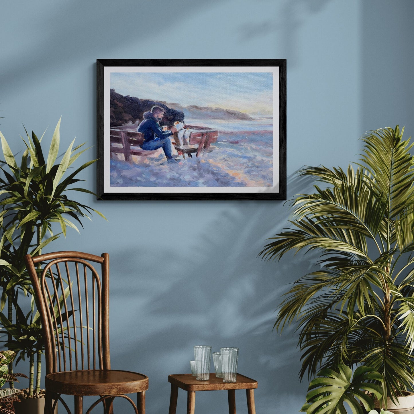 Framed artwork of a man and his dog hanging on a blue wall with plants and furniture below.