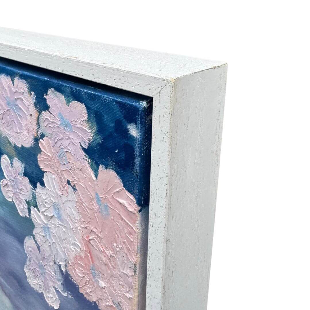 Close-up of textured blush-pink flowers and the top-right corner of the pale wooden frame on Be True.