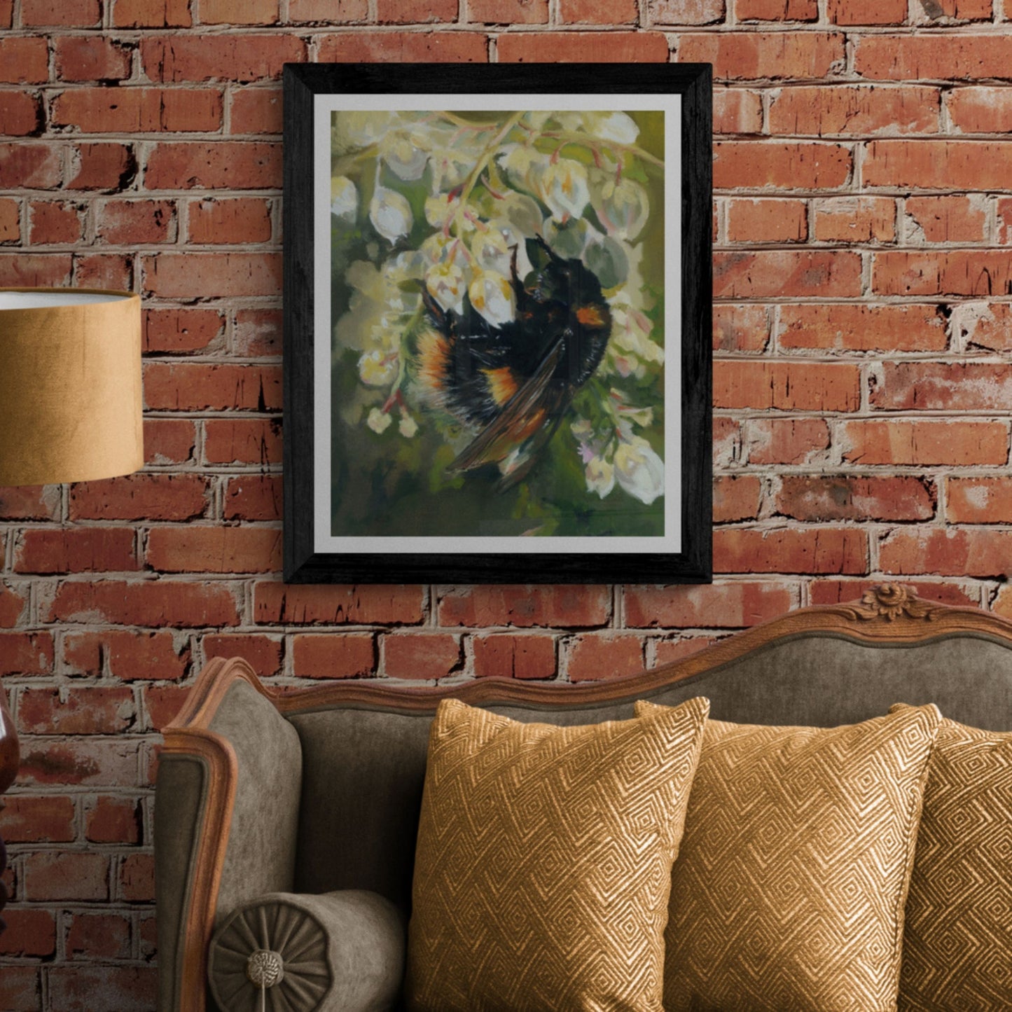 Bumble Bee Wall Art in black frame on brick wall above green sofa. 