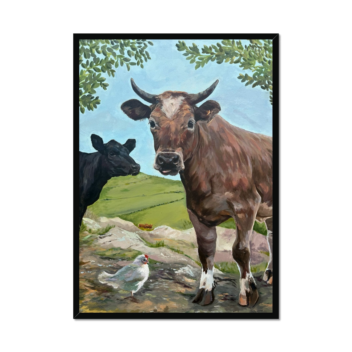 Cheeky Cows art print in a black frame, featuring two playful cows and their friend the chicken in a countryside field.
