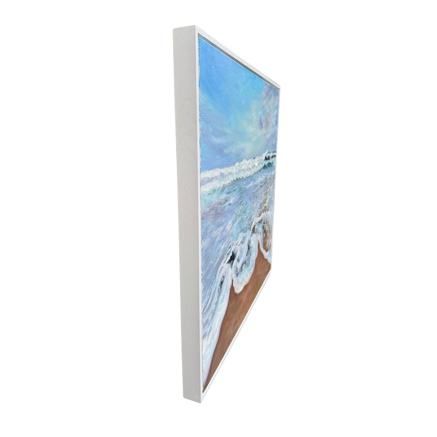Side view of framed oil painting of a beach scene with frothy waves and pastel sky