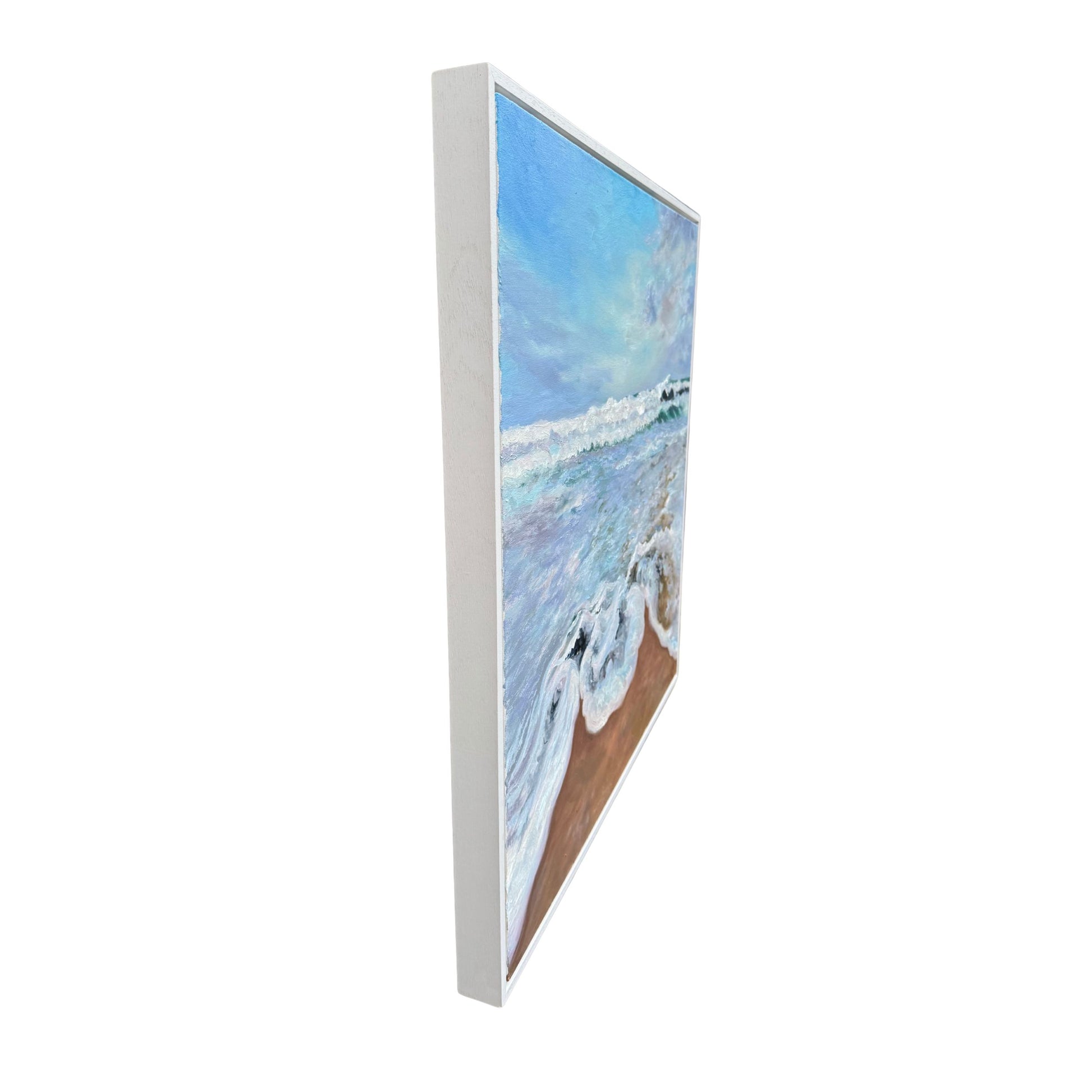 Side view of framed oil painting of a beach scene with frothy waves and pastel sky