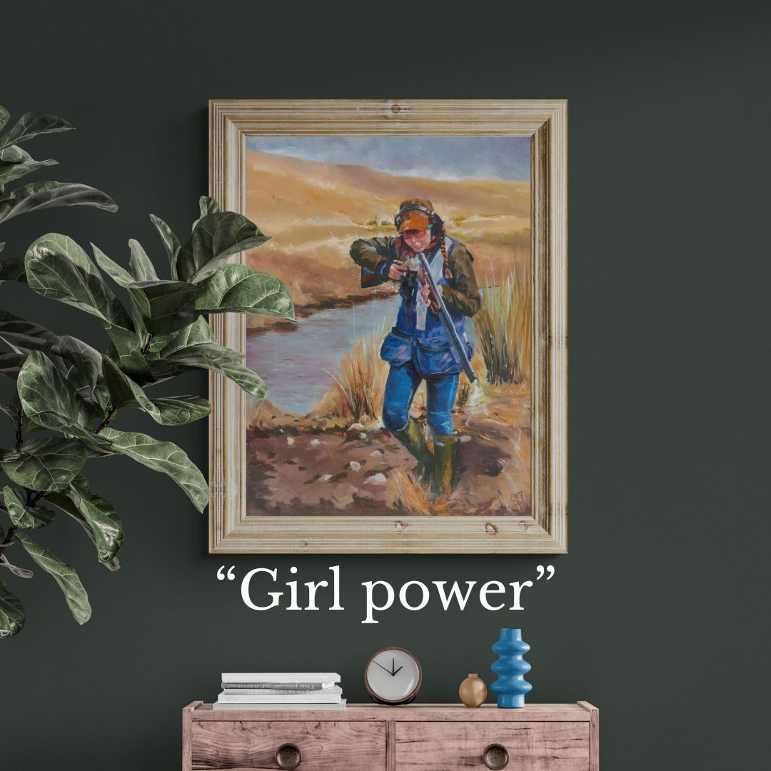 Framed artwork of a young girl shooting clays in a natural setting with 'Girl power' text below on a dark wall.