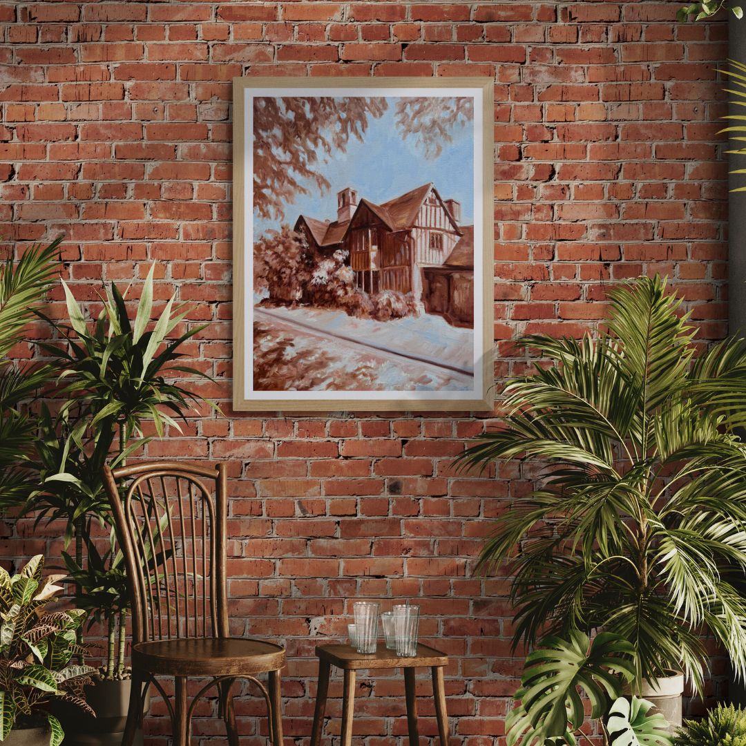 Framed artwork of a Shakepearean house in natural frame option on a brick wall with plants and a chair in the foreground