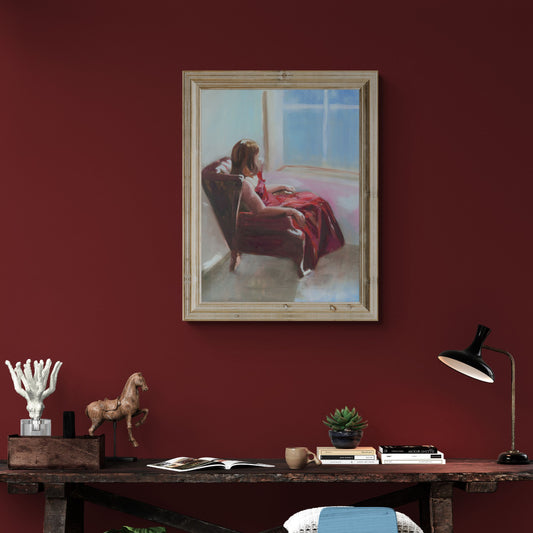 Framed painting of a woman in a red ballgown on a red wall above a wooden desk.