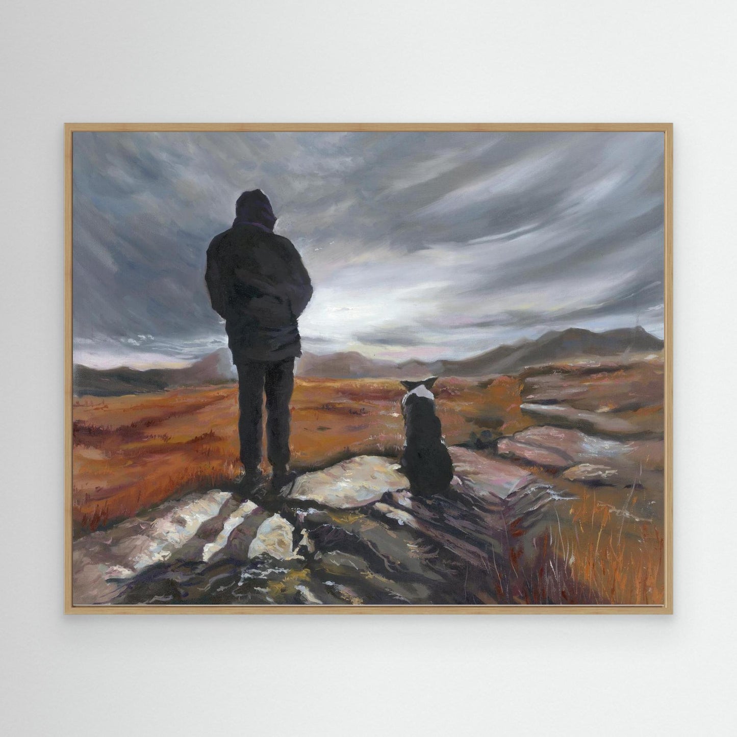 Man and a dog canvas art print standing on a rock with a dramatic sky beyond.