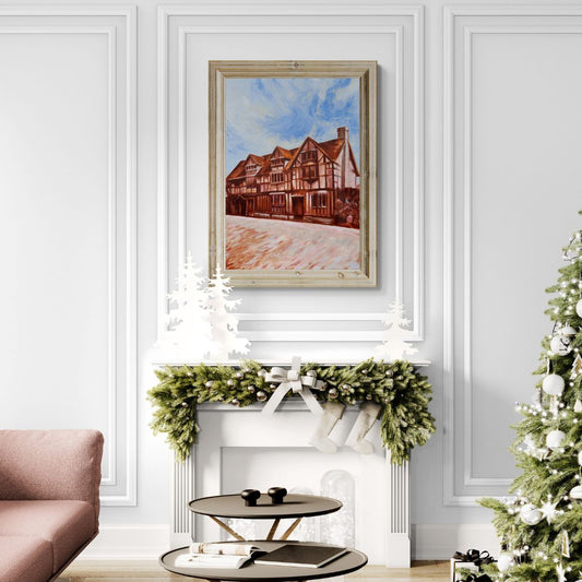 Original oil painting of Shakespeare’s Birthplace in Stratford-upon-Avon by artist Lorraine Field, displayed in a natural wood frame above a festive fireplace with Christmas greenery and a tree nearby.