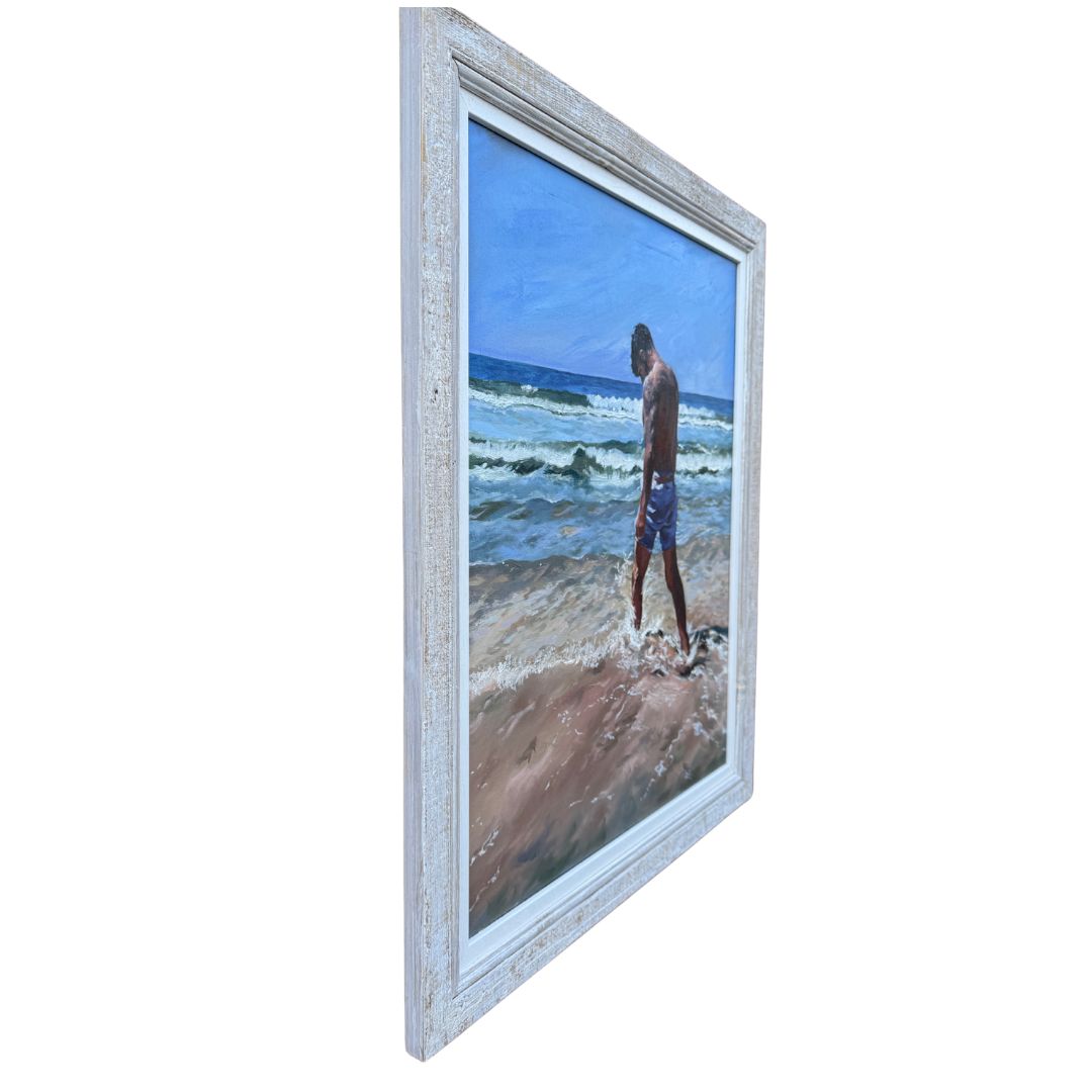 Close up of left hand side of framed oil painting of a man kicking surf on a beach in Cornwall