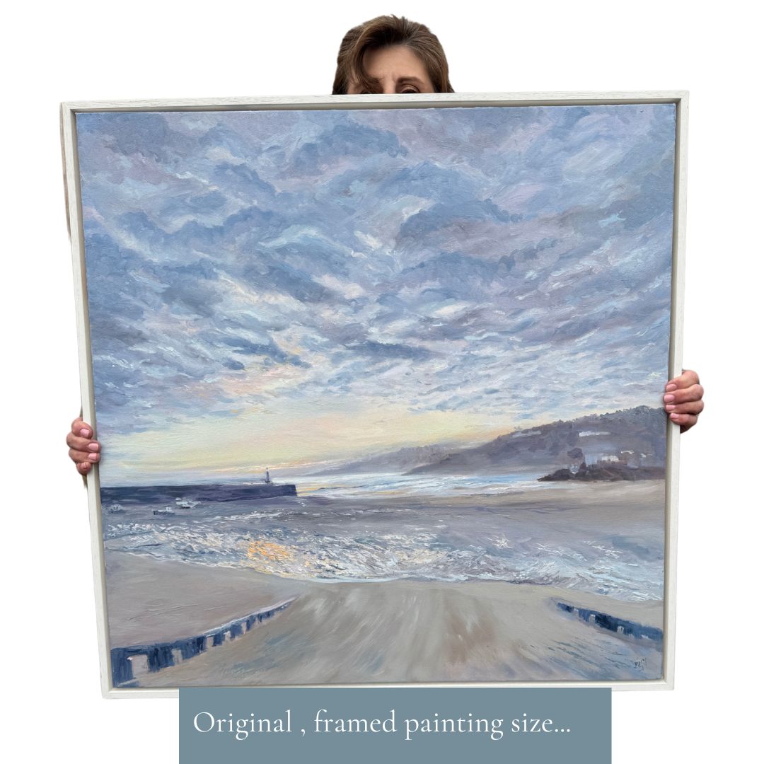 Woman holding a large framed oil painting of St Ives Harbour at sunrise, showcasing the original artwork’s scale. 