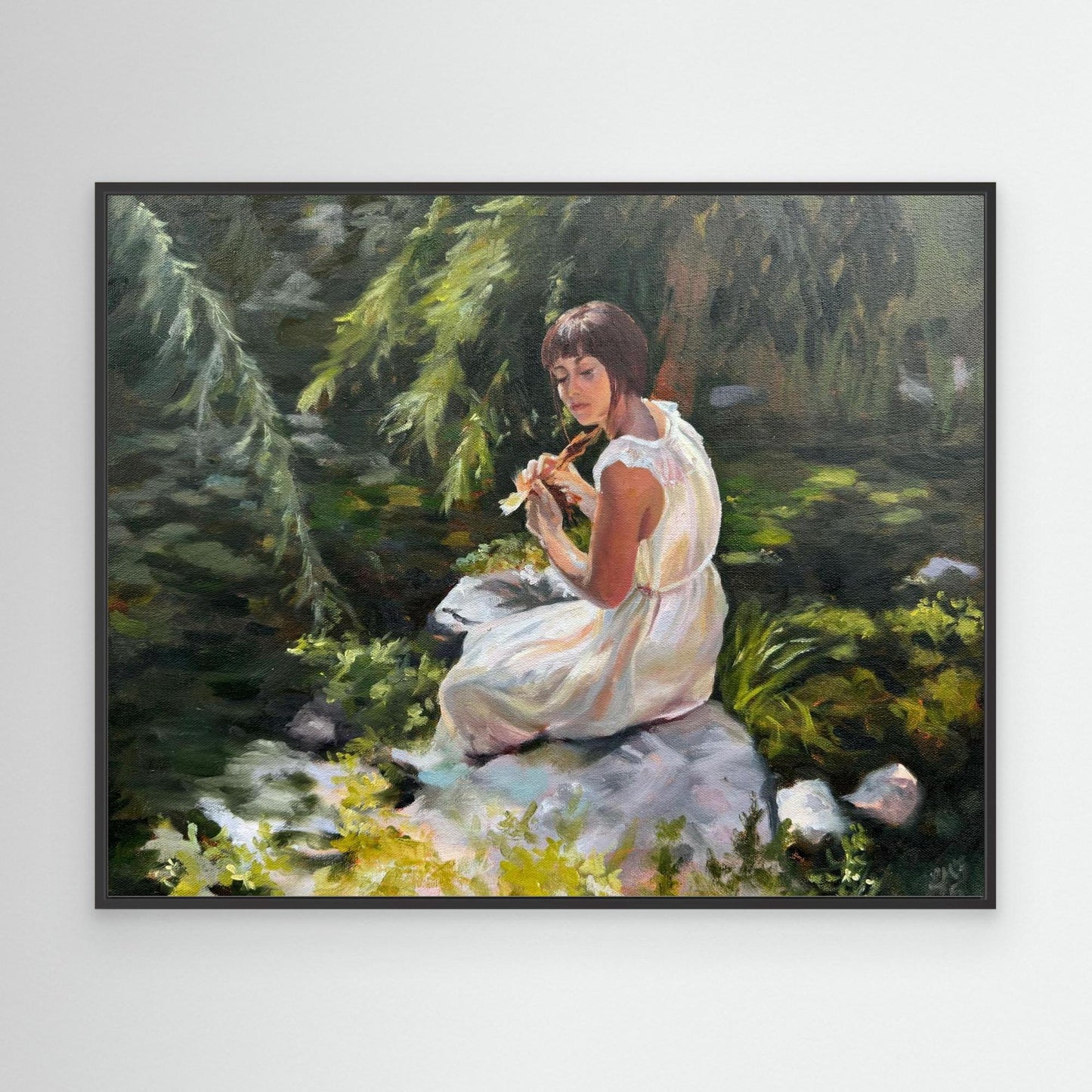 Black framed woodland canvas print showing a contemplative woman surrounded by soft green foliage and reflective light.