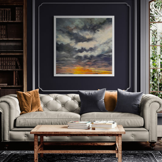 Moody sunrise art print of Lelant in Cornwall in white wooden frame above cream leather sofa.
