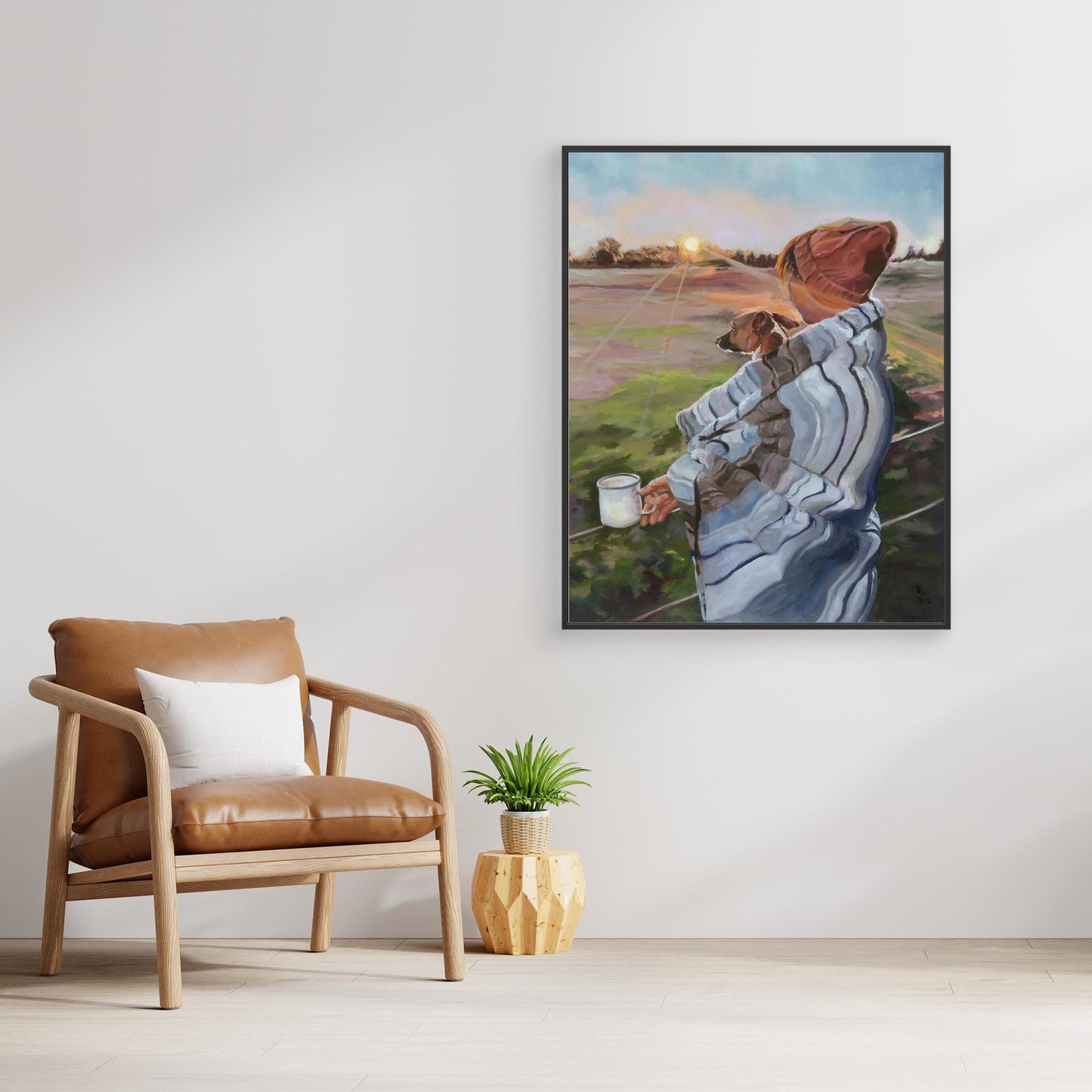 Framed artwork of a person with a Jack Russell dog on a wall in a room with a brown chair and plant.