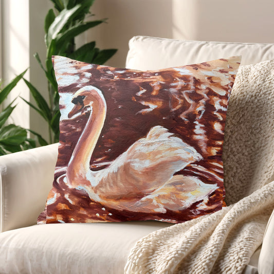 Cushion featuring a swan painting placed on a cosy armchair in a warmly lit room.