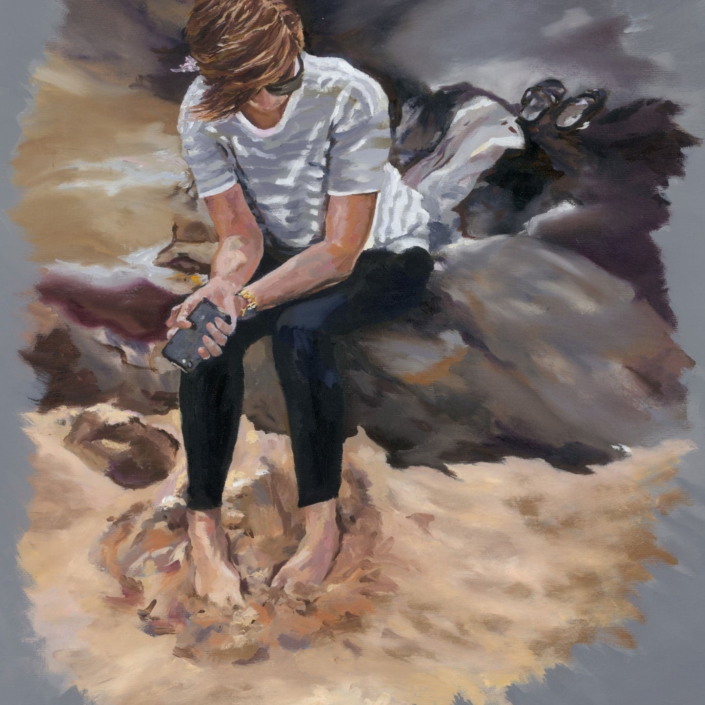 A young lady sitting on a rock using a smartphone with a sandy landscape in the background