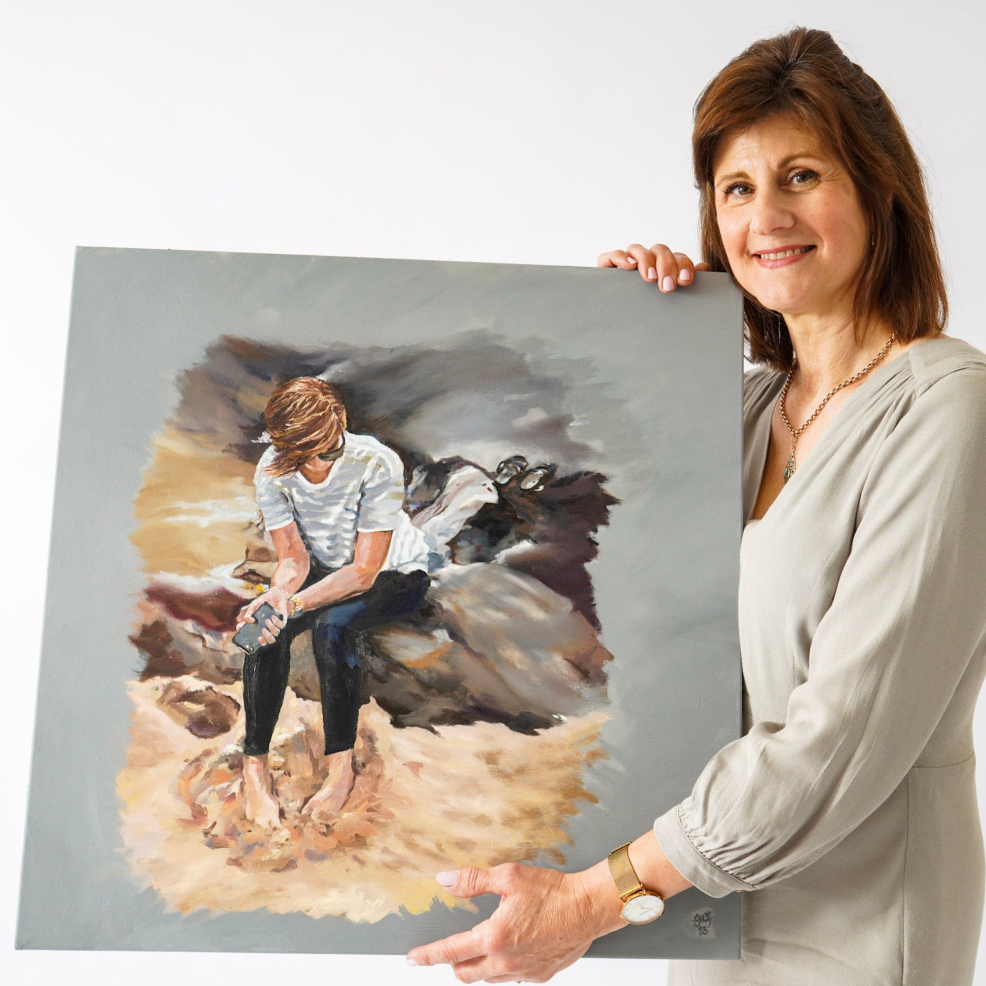 Lorraine Field Artist holding an oil painting of a young lady sitting on a rock.