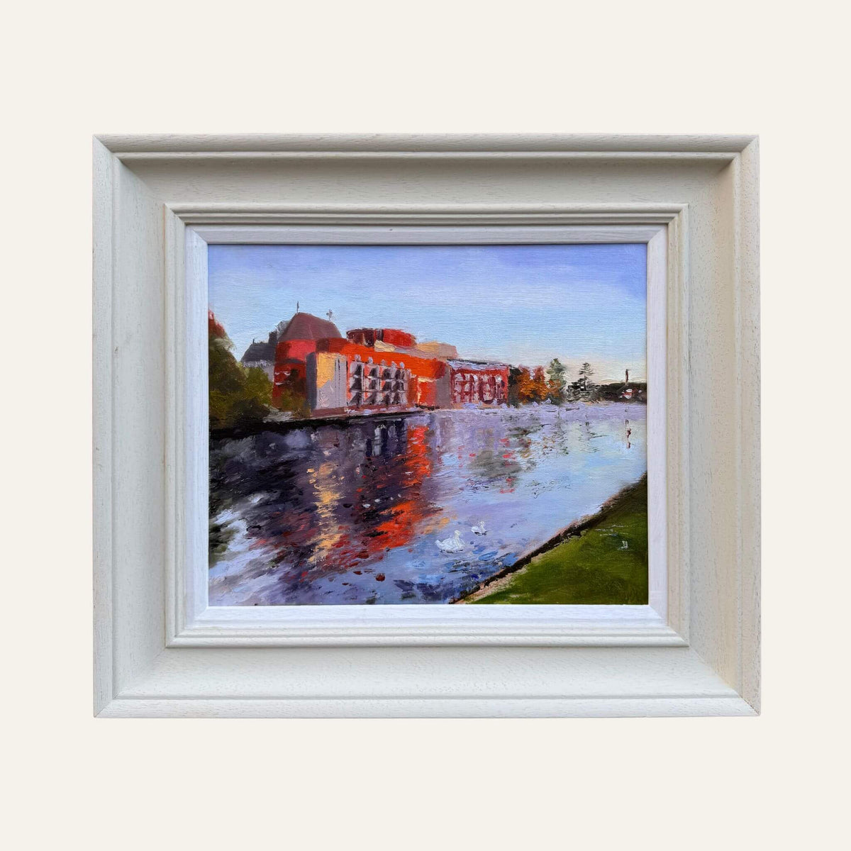 Original oil painting of the Royal Shakespeare Theatre beside the River Avon, with orange and blue reflections, in a pale painted frame.