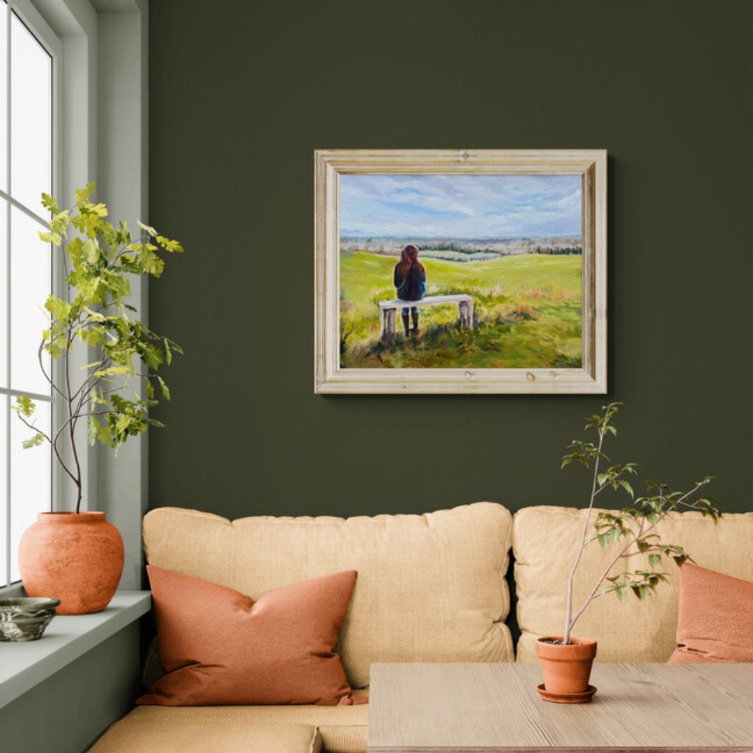 Original oil painting of a woman sitting alone on a bench overlooking rolling countryside beneath a blue sky, by British artist Lorraine Field.