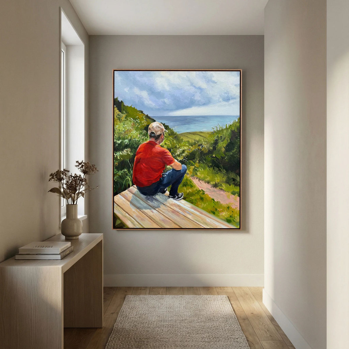 Just taking it in framed canvas print showing a person enjoying a countryside view from a bench, displayed in a neutral hallway.