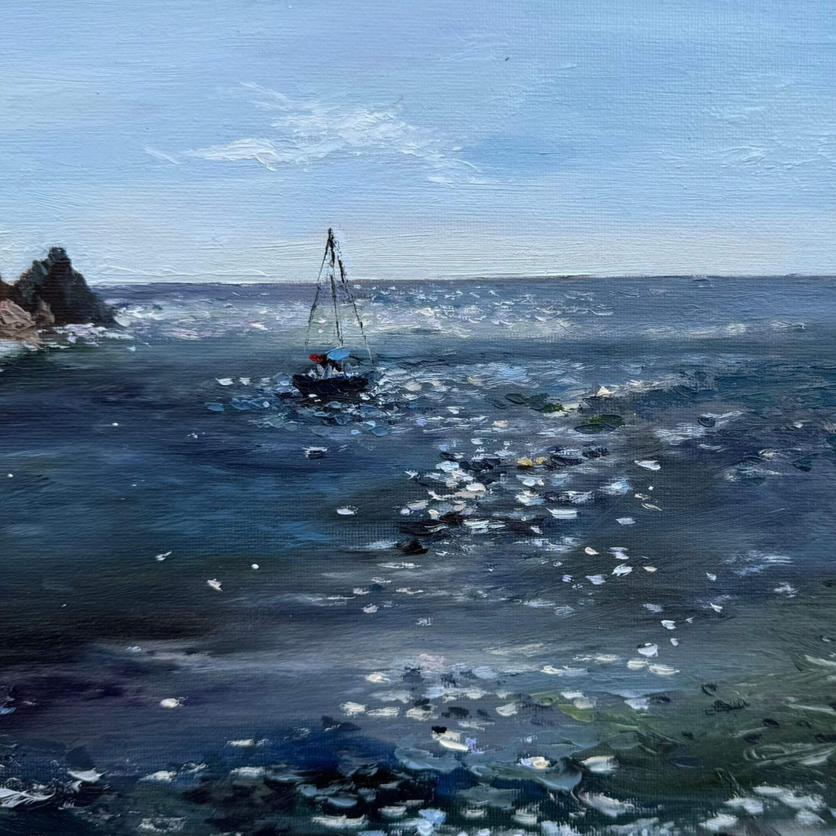 Close up view of Lamorna Cove oil painting by Lorraine Field, showing a sailing boat on sparkling blue water in a pale wooden frame.