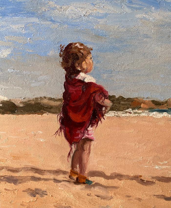 Little girl dressed in cerise shawl on beach